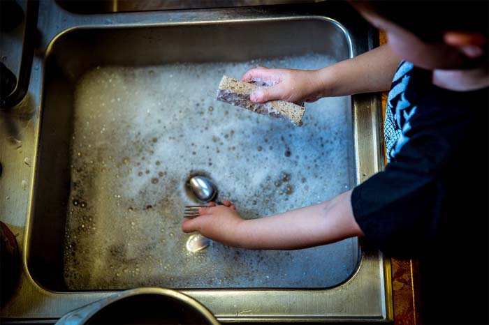 Child Washing Utensils in Sink